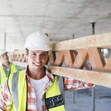 Construction worker carrying girder on construction site Construction worker carrying girder on construction site